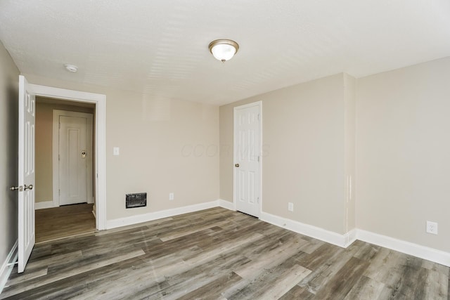 spare room featuring dark hardwood / wood-style flooring and a textured ceiling