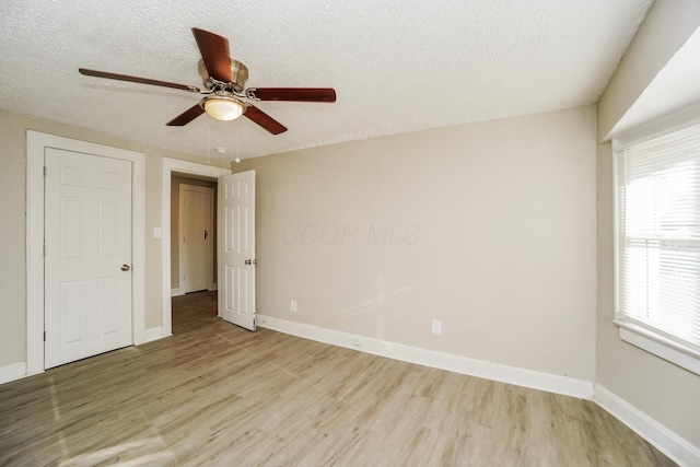 unfurnished bedroom featuring ceiling fan, multiple windows, a textured ceiling, and light hardwood / wood-style flooring