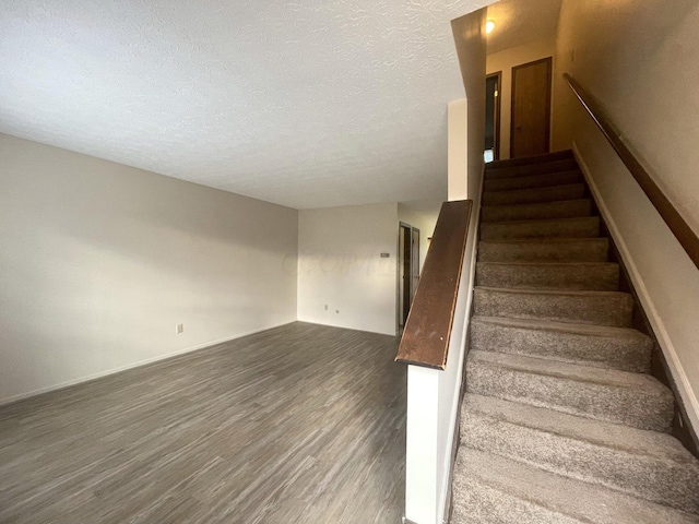 staircase featuring wood-type flooring and a textured ceiling