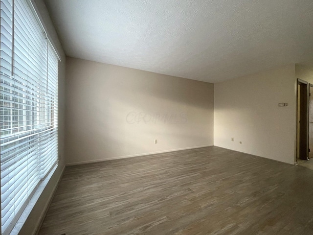 unfurnished room featuring dark wood-type flooring and a textured ceiling