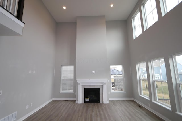 unfurnished living room with a fireplace, a high ceiling, and hardwood / wood-style floors