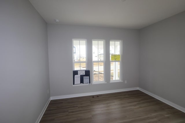 empty room with baseboards and dark wood-style flooring