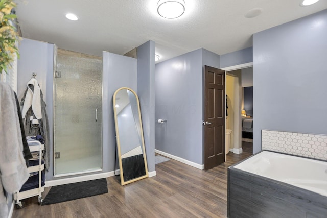 bathroom with wood-type flooring, a textured ceiling, and shower with separate bathtub