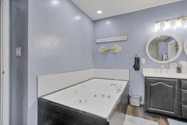 bathroom with tiled bath, vanity, and wood-type flooring