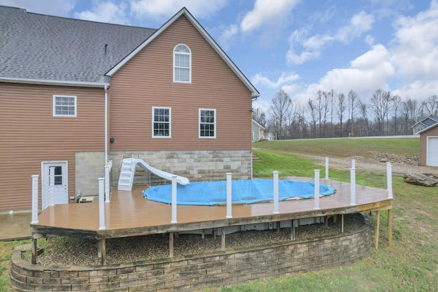 back of house featuring a pool side deck and a lawn