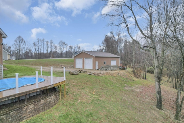 view of yard featuring a garage, an outdoor structure, and a wooden deck