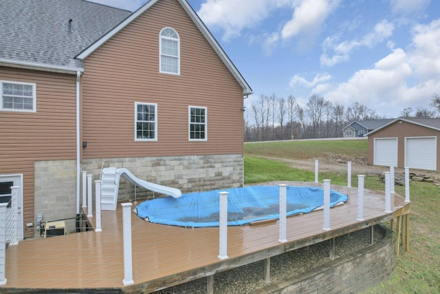 view of pool featuring a wooden deck, an outdoor structure, and a water slide