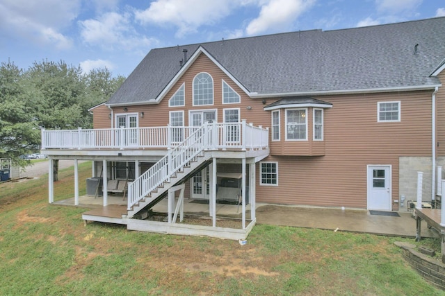 rear view of property featuring a lawn, a wooden deck, and a patio