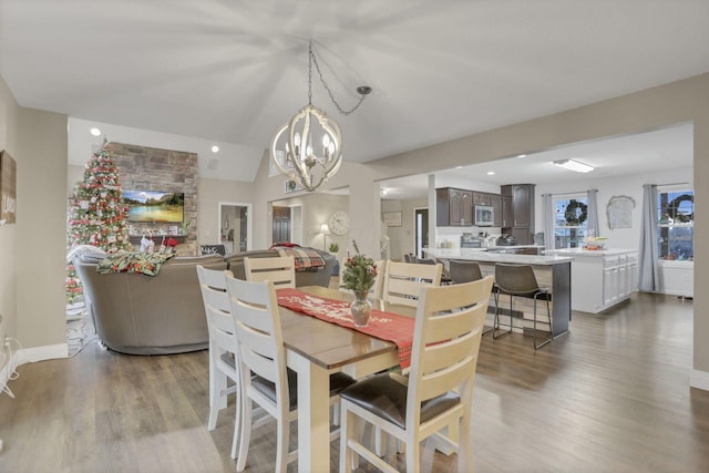 dining room featuring vaulted ceiling, a chandelier, and light hardwood / wood-style flooring