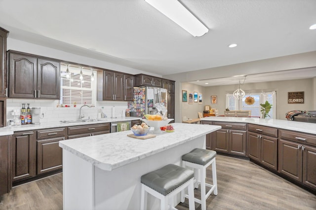 kitchen with a center island, a kitchen breakfast bar, wood-type flooring, appliances with stainless steel finishes, and dark brown cabinetry