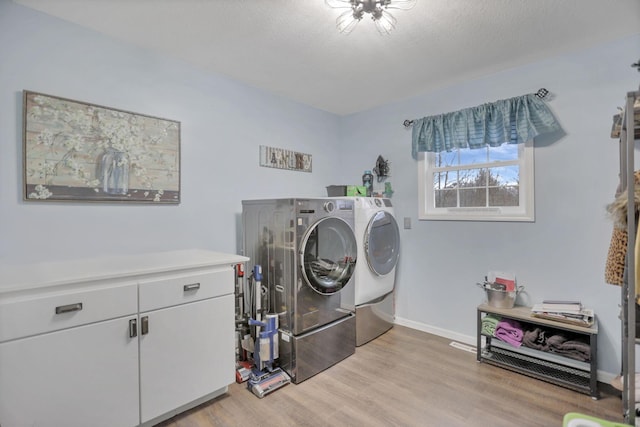 washroom with light hardwood / wood-style floors, cabinets, a textured ceiling, and washing machine and clothes dryer