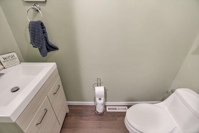 bathroom featuring wood-type flooring, vanity, and toilet