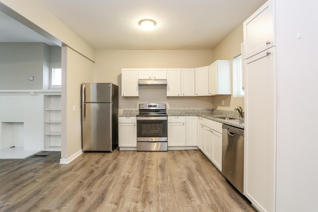 kitchen featuring white cabinetry, sink, light stone countertops, light hardwood / wood-style flooring, and appliances with stainless steel finishes