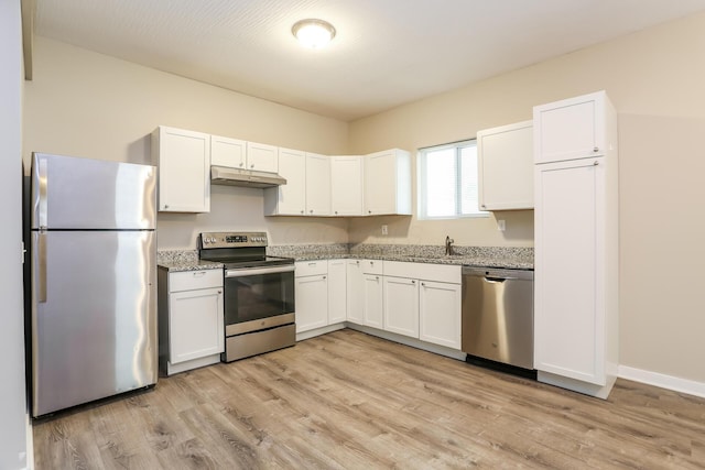 kitchen featuring light stone countertops, sink, light hardwood / wood-style floors, white cabinets, and appliances with stainless steel finishes