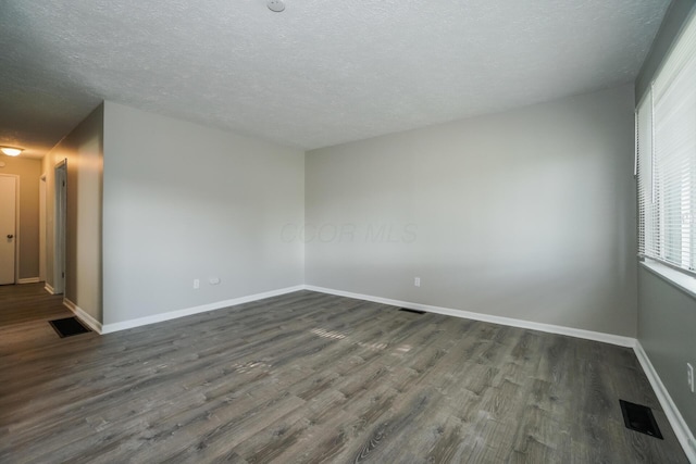 empty room featuring dark hardwood / wood-style floors and a textured ceiling