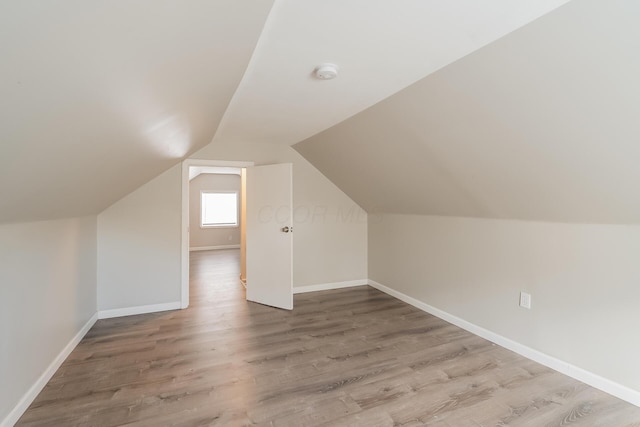 additional living space with hardwood / wood-style floors and lofted ceiling