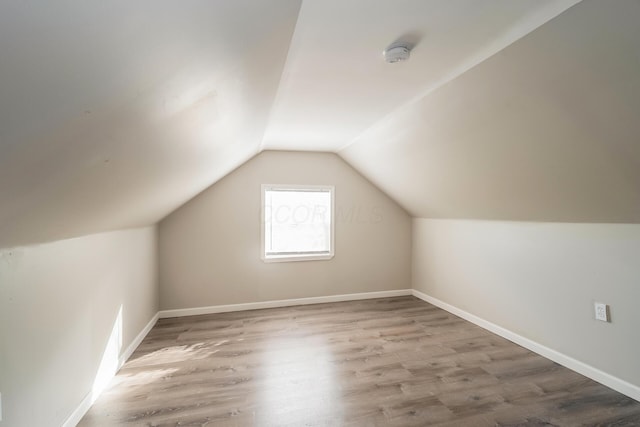 additional living space with wood-type flooring and vaulted ceiling