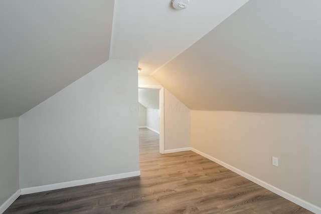 additional living space with wood-type flooring and vaulted ceiling