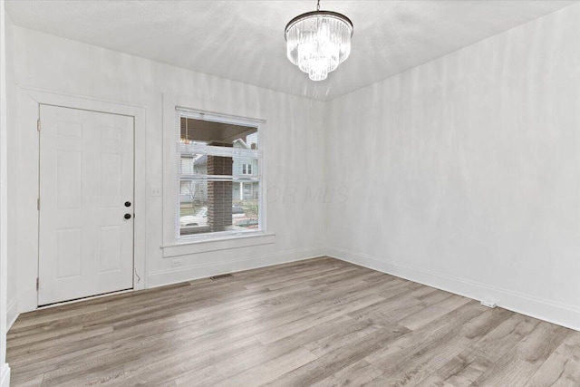 unfurnished dining area featuring a chandelier and light hardwood / wood-style flooring