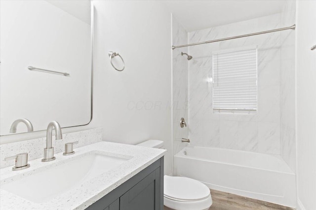 full bathroom with vanity, hardwood / wood-style flooring, toilet, and tiled shower / bath