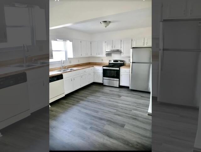 kitchen with appliances with stainless steel finishes, white cabinetry, dark wood-type flooring, and sink