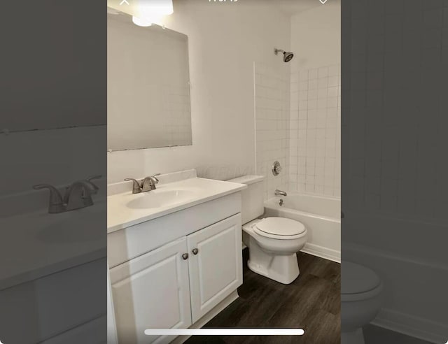 full bathroom with vanity, hardwood / wood-style flooring, toilet, and tiled shower / bath