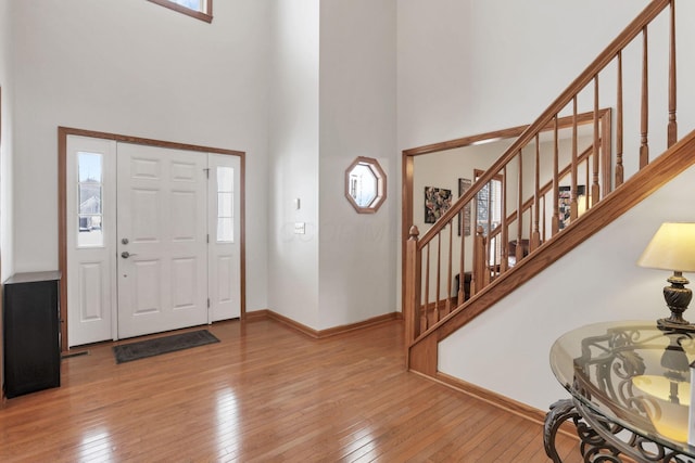 foyer with a towering ceiling and light wood-type flooring