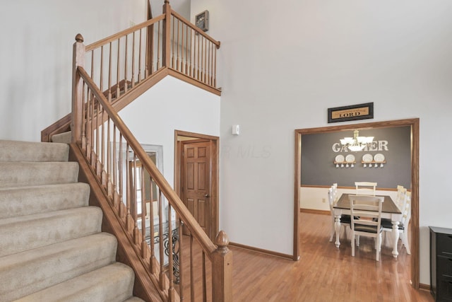 stairway featuring hardwood / wood-style floors, a towering ceiling, and a chandelier