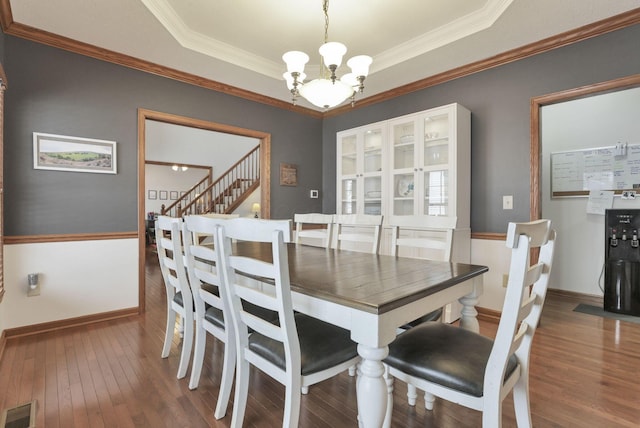 dining room featuring dark hardwood / wood-style flooring, crown molding, and a notable chandelier