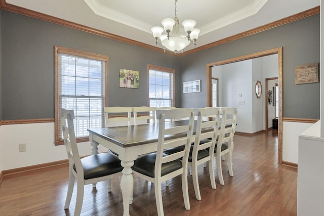 dining room with a chandelier, hardwood / wood-style floors, a tray ceiling, and ornamental molding