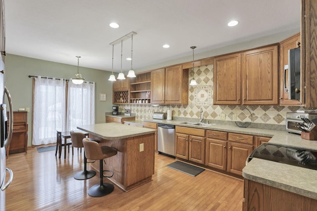 kitchen featuring a center island, sink, stainless steel dishwasher, pendant lighting, and a kitchen bar