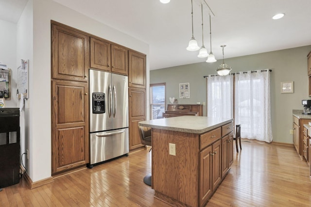 kitchen featuring plenty of natural light, a center island, stainless steel fridge with ice dispenser, and hanging light fixtures