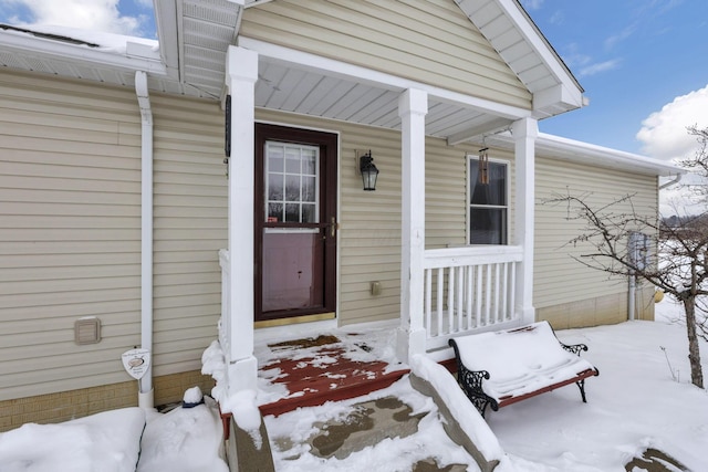 snow covered property entrance with a porch