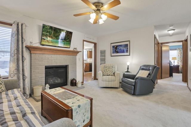 carpeted living room with ceiling fan and a brick fireplace