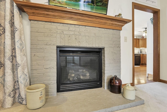 interior details featuring carpet flooring, dishwashing machine, ceiling fan, and a brick fireplace