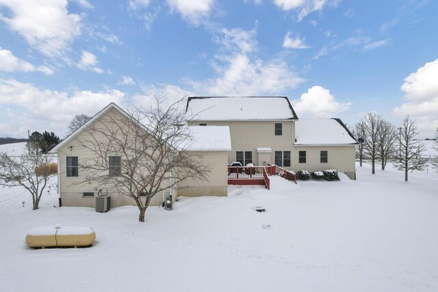 snow covered back of property with central AC unit and a wooden deck