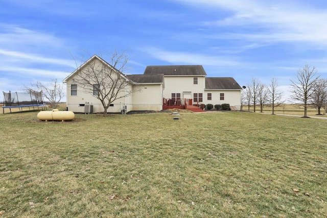 back of house featuring a trampoline, a lawn, and central air condition unit