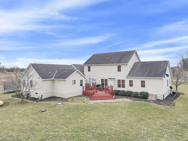 back of property featuring a trampoline, a yard, and a deck