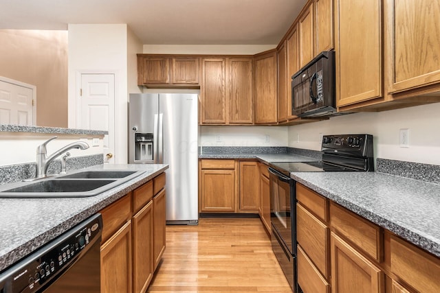 kitchen featuring sink, black appliances, and light hardwood / wood-style flooring