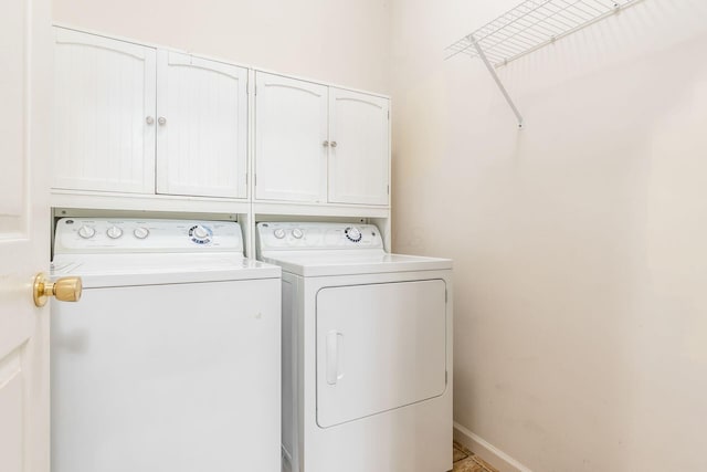 clothes washing area with washer and clothes dryer and cabinets