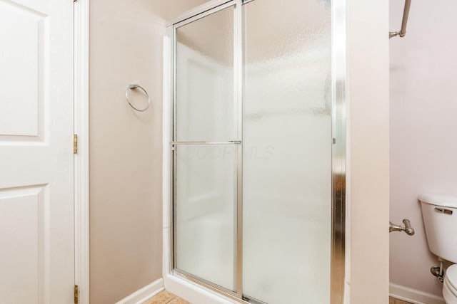 bathroom with a shower with shower door and toilet