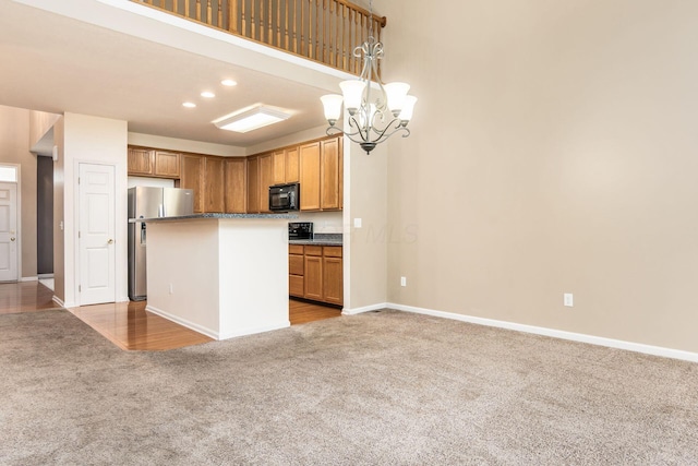 kitchen with stainless steel fridge, pendant lighting, a notable chandelier, carpet floors, and a kitchen island