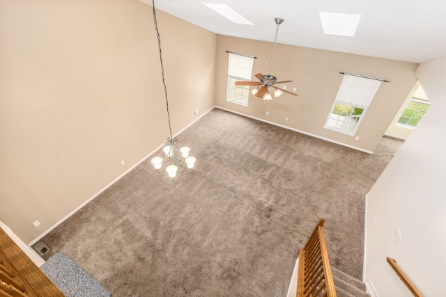 unfurnished living room with a skylight, carpet floors, and ceiling fan with notable chandelier