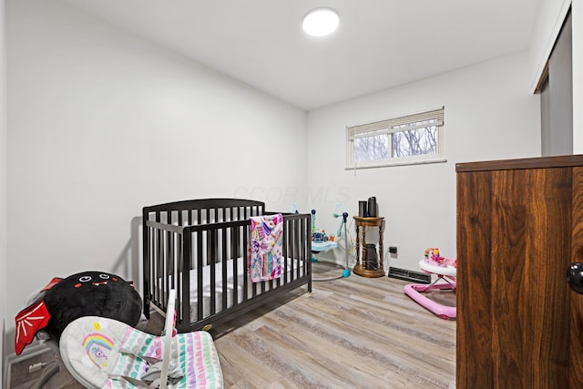 bedroom featuring light hardwood / wood-style flooring and a nursery area