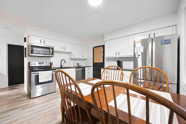 kitchen with white cabinetry, sink, tasteful backsplash, light hardwood / wood-style floors, and appliances with stainless steel finishes