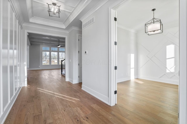 corridor with an inviting chandelier, baseboards, crown molding, and wood finished floors