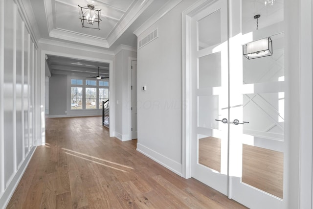 hallway featuring wood finished floors, visible vents, baseboards, french doors, and crown molding