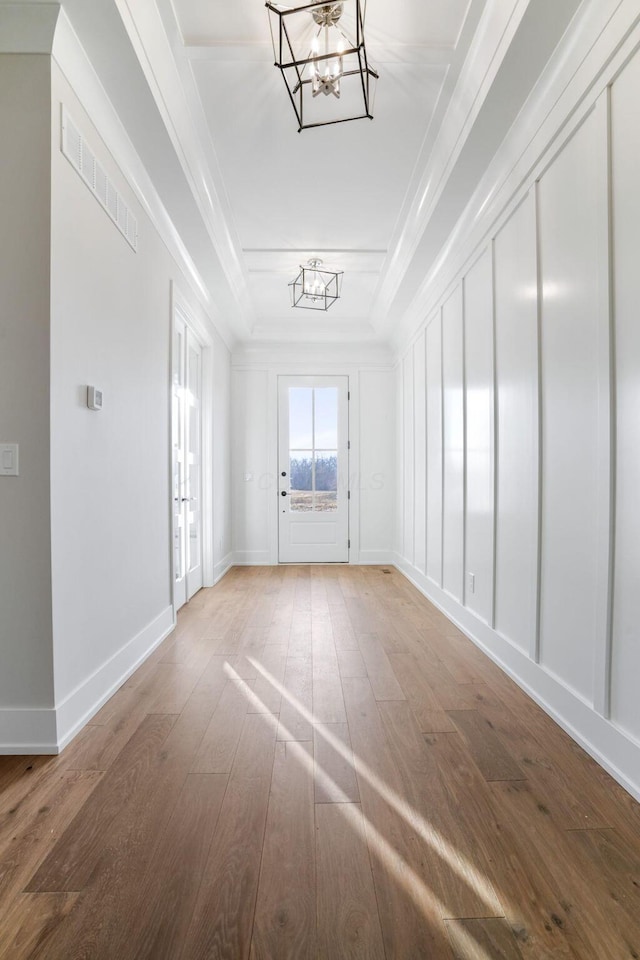 unfurnished room featuring crown molding, a decorative wall, hardwood / wood-style flooring, and a notable chandelier