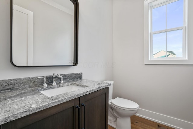 bathroom featuring toilet, wood finished floors, vanity, and baseboards