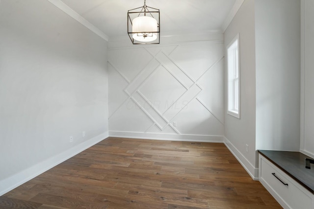 unfurnished dining area with ornamental molding, dark wood-style flooring, and baseboards